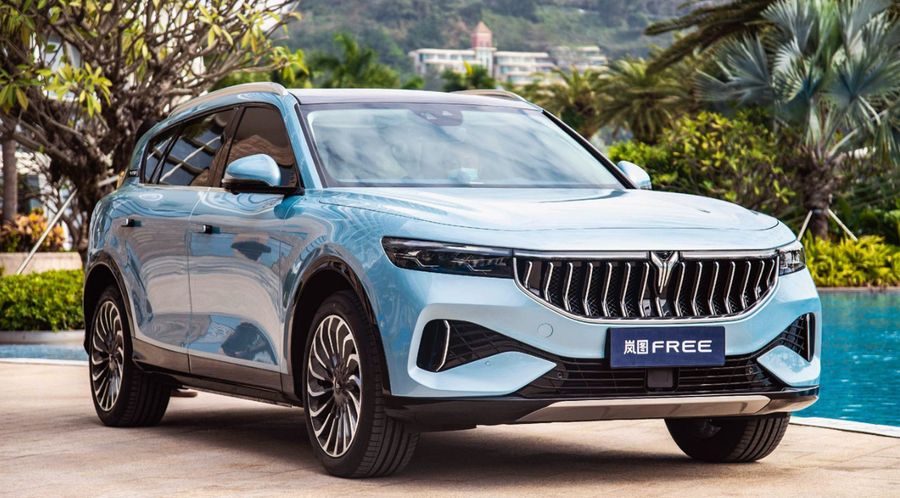 Világoskék Voyah prémium elektromos SUV egy üvegportálos magyar autószalon előtt, fotórealisztikus városi környezetben.