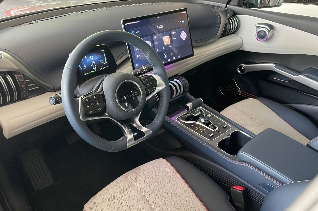 Modern elektromos autó belső dizájn: a BYD Atto 3 utastere kék és bézs árnyalatú műszerfallal, yacht stílusú menetválasztó karral és digitális kijelzőkkel.